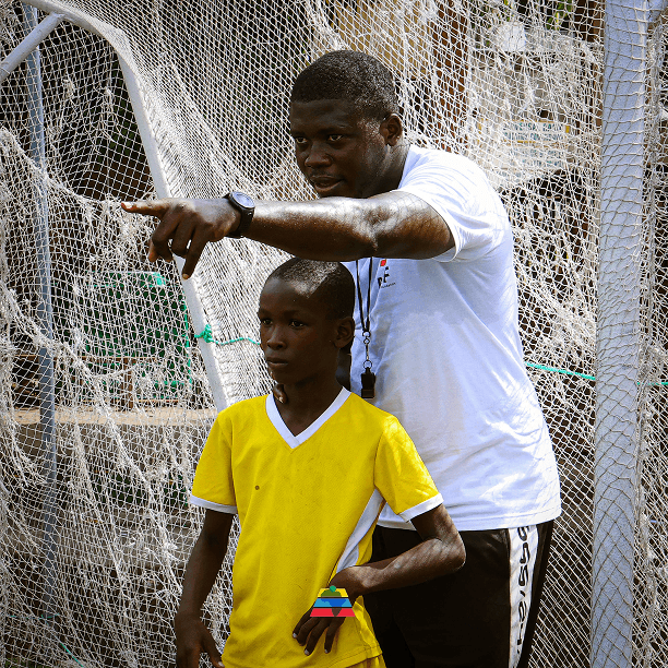A coach guiding a young athlete at training